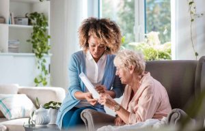 A senior support professional, assisting an elderly women with financial documentation.