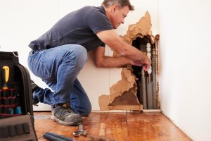 professional attending a plumbing issue in a drywall